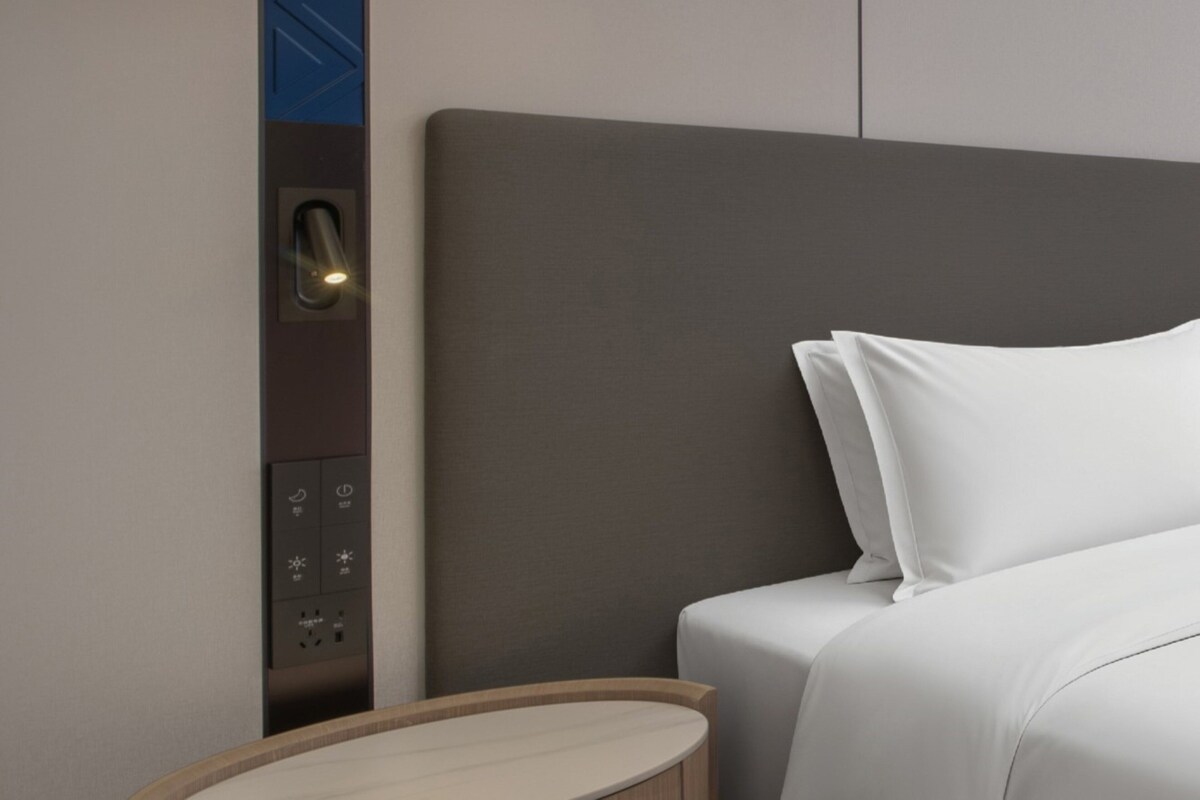Ein modernes Hotelzimmer mit einem Bett, einem Nachttisch und einer Bedienanlage für die Zimmereinrichtungen.