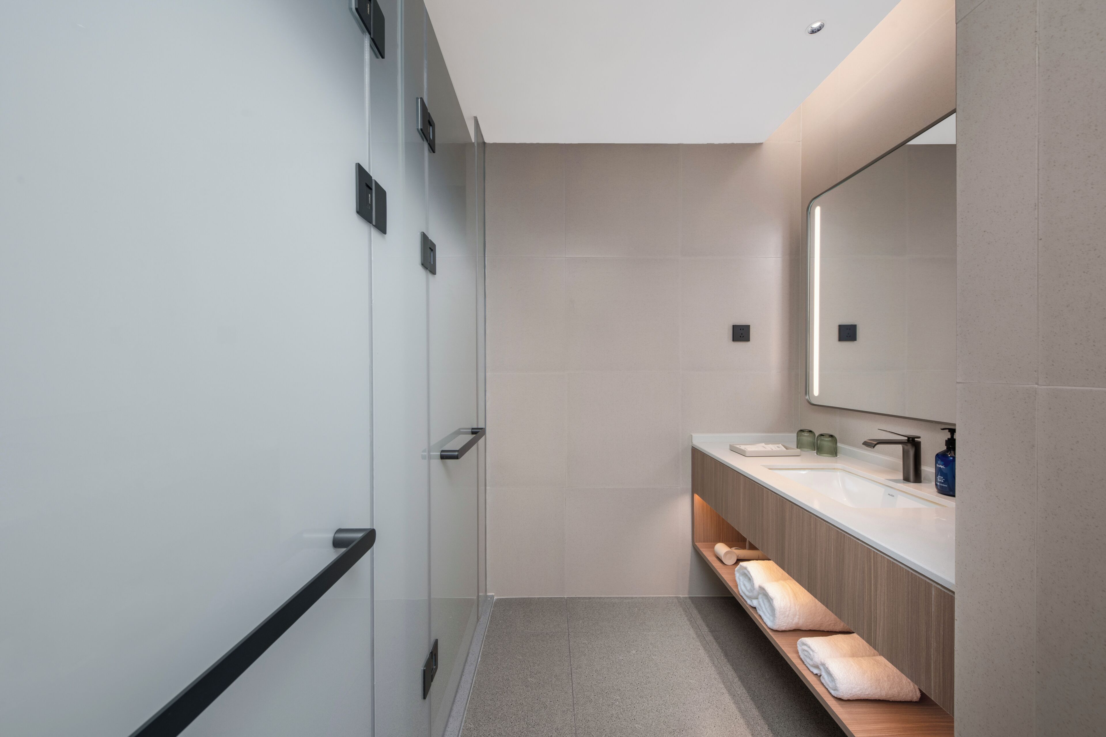 Un baño moderno con un espejo grande, dos lavamanos y un perchero para toallas.