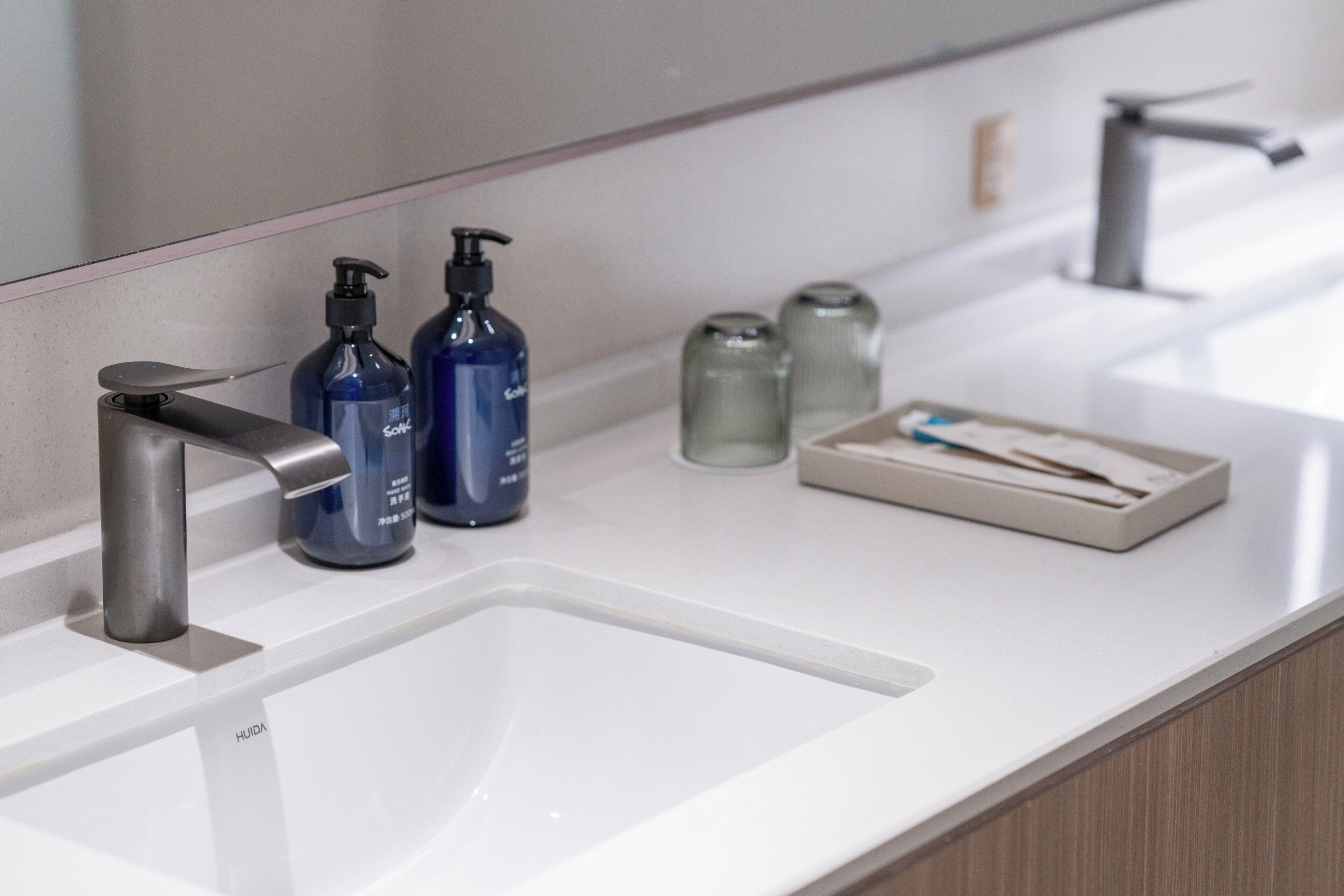 Un baño moderno con un lavamanos blanco, un grifo plateado y dos dispensadores de jabón azules.