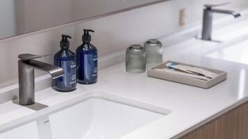 A modern bathroom with a white sink, a silver faucet, and two blue soap dispensers.