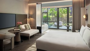 A hotel room with a bed, a sofa, a TV, a small table with a vase of flowers, and a view of the outside. - Kimpton Nine Trees Shanghai By Ihg (Shanghai)