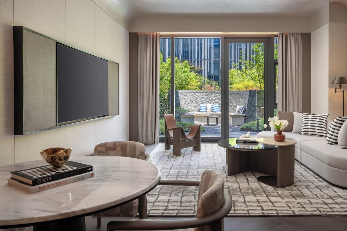 Una sala de estar moderna con un sofá, sillas, una mesa de centro y un televisor.