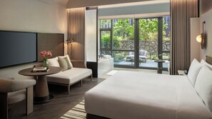 A hotel room with a bed, a sofa, a TV, a small table with a vase of flowers, and a view of the outside. - Kimpton Nine Trees Shanghai By Ihg (Shanghai)