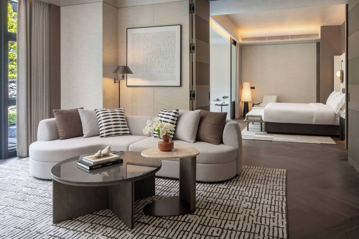 Una habitación de hotel moderna con sofá, una mesita redonda, cama y vistas al exterior.