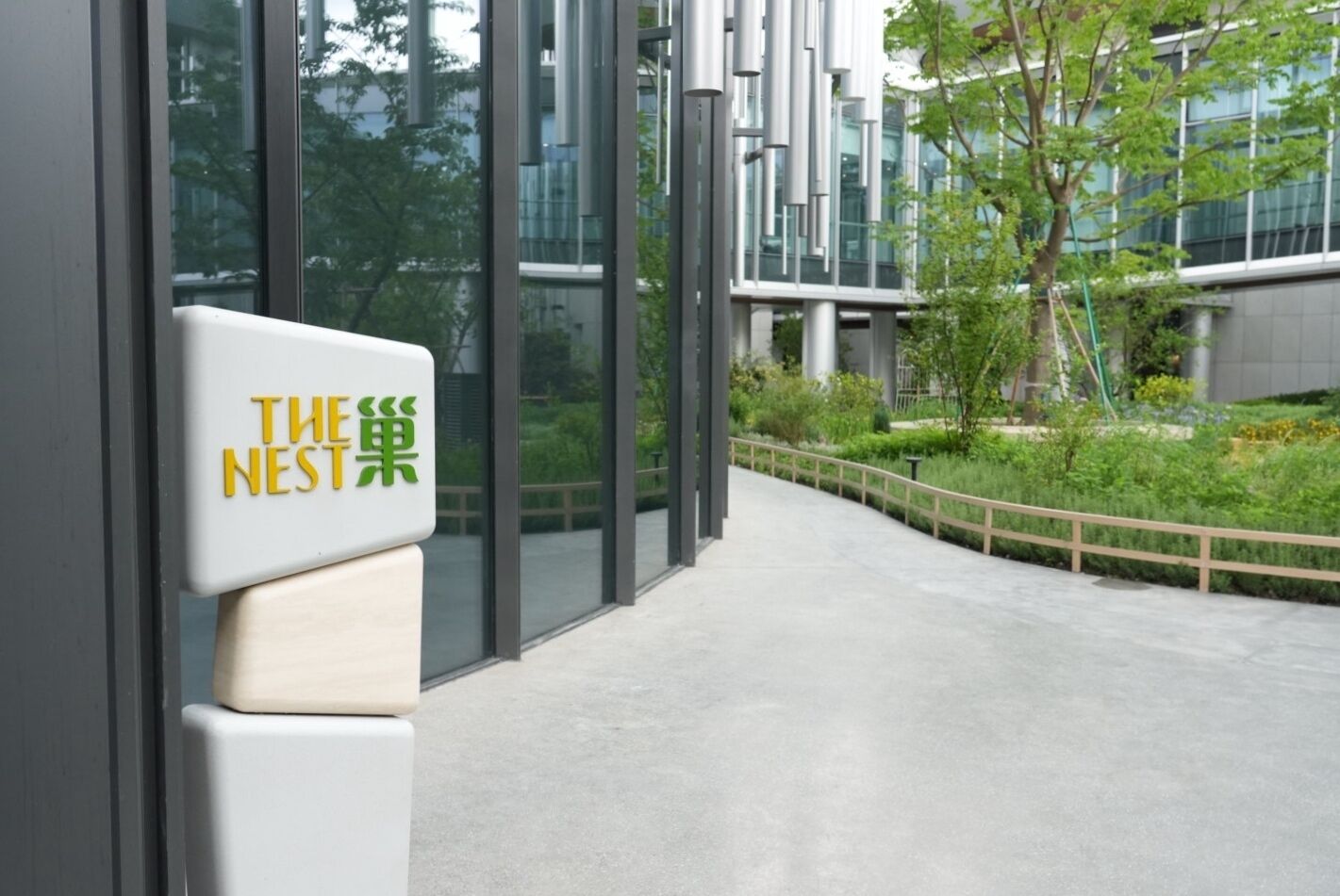 L'ingresso di un edificio moderno con un cartello che recita 'THE NEST' in giallo e verde.