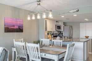 A modern kitchen with a central island, white cabinetry, and a pendant light fixture. - Point Emerald D-104, Oceanview 3BR 3BA Emerald Isle! (Emerald Isle)