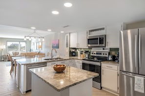 A modern kitchen with granite countertops, stainless steel appliances, and a central island. - Point Emerald D-104, Oceanview 3BR 3BA Emerald Isle! (Emerald Isle)