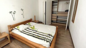 A bedroom with a bed, a wooden nightstand, a small stool, a wardrobe, and a mirror. - T3 Sanary-Sur-Mer for rent Holiday 2026 (Sanary-sur-Mer)