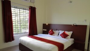 A hotel room with a large bed, red curtains, a window with bars, and a nightlight. - Blueway Residency BusinessBoutique Hotel (Thiruvananthapuram)
