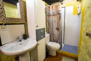 A bathroom with a sink, toilet, shower, and a mirror with a mosaic border.