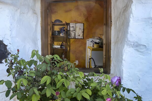 A rustic room with a wooden door, a shelf with various items, and a small window with a plant in the foreground. - Country House 'Los Pasos Grandes' with Sea Views, Private Terrace and Wi-Fi (Villa de Valverde)