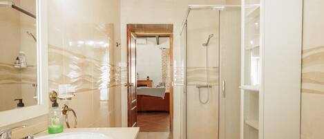 Un baño moderno con ducha de vidrio, un lavamanos grande de color blanco y un espejo con apliques de pared.