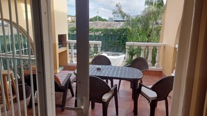 Un balcone con tavolo e sedie, vista su una casa e ringhiera bianca.