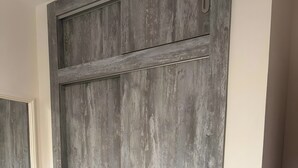 Una stanza con una cassettiera in legno, un armadio grande e uno specchio a parete.