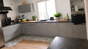 A modern kitchen with grey cabinets, a black countertop, a window, and a potted plant. - Spacious 5-bedroom villa with AC in perfect Claret (Claret)