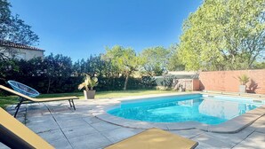 A swimming pool with lounge chairs, a clear blue sky, and surrounding greenery. - Spacious 5-bedroom villa with AC in perfect Claret (Claret)