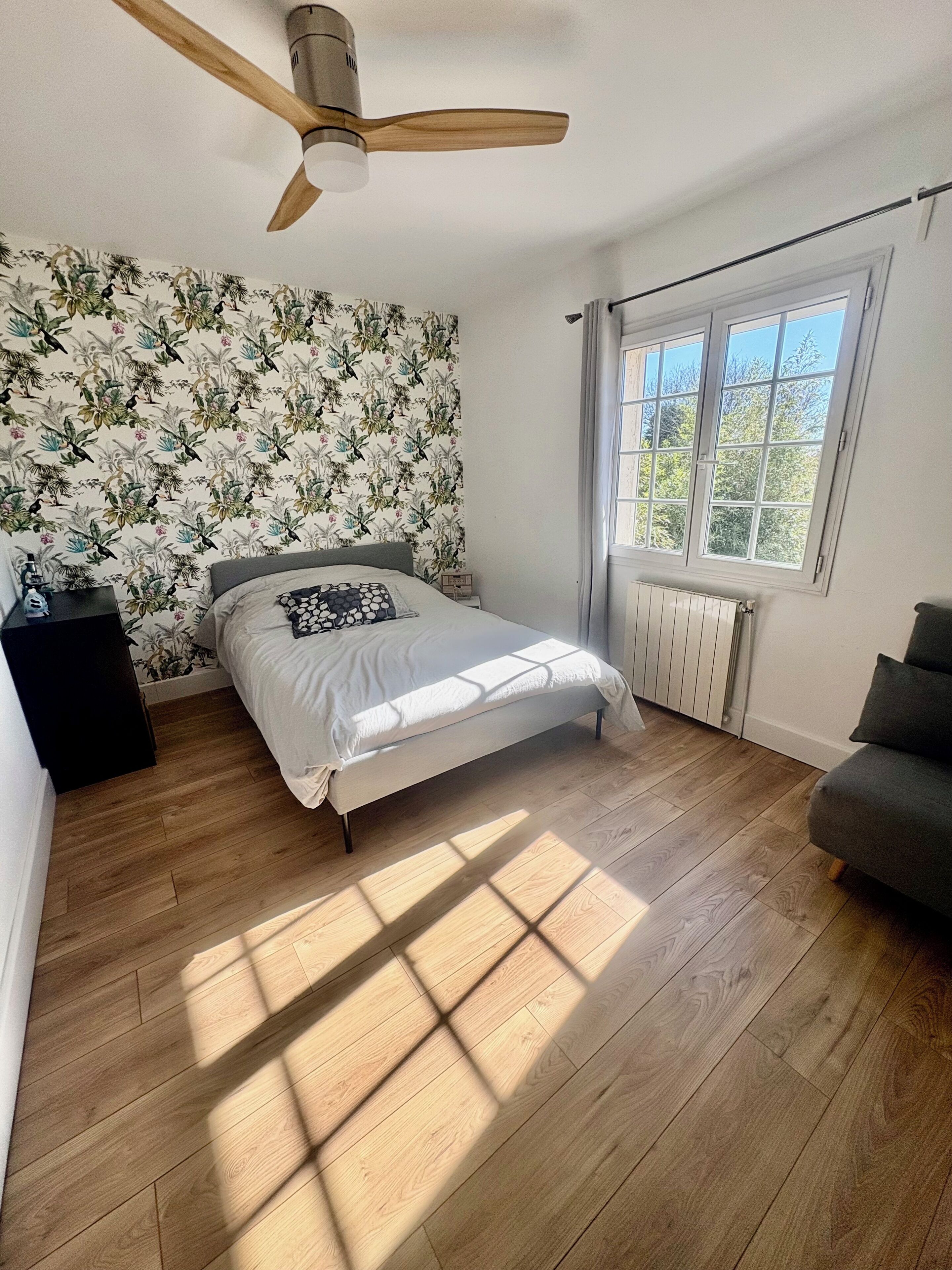 Ein Schlafzimmer mit Bett, Deckenventilator, Heizkörper und Fenster.