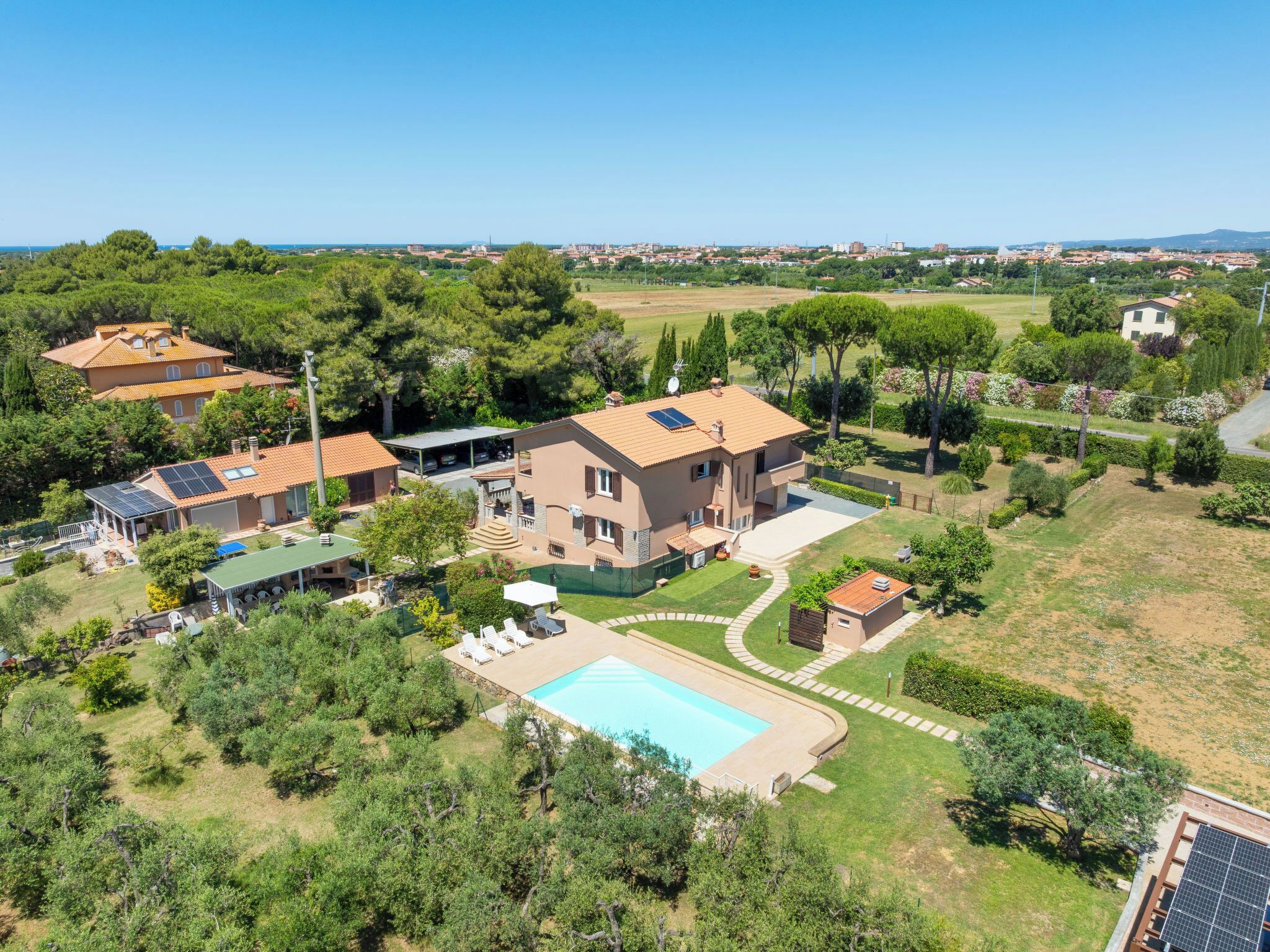 Une grande maison avec une piscine, des panneaux solaires et un jardin.