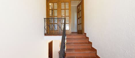 A staircase with a metal railing leading to a wooden door with glass panels.