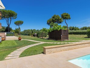 Ein Garten mit Swimmingpool, Kiesweg und Holzzaun.