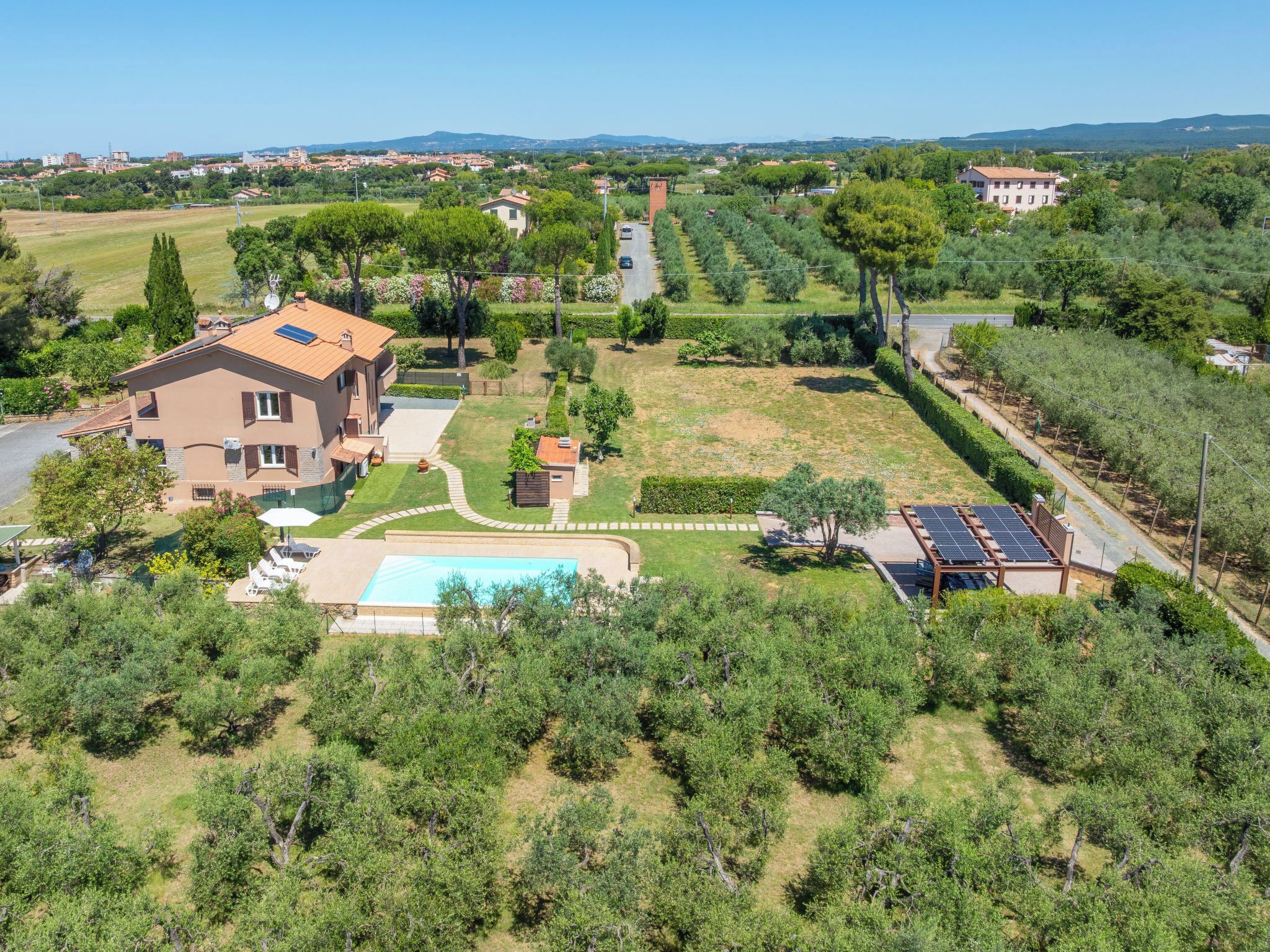 Un'ampia casa con piscina, pannelli solari e un giardino curato.