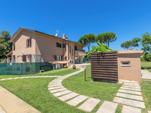 A two-story house with a paved driveway, a fenced garden, and a small wooden structure. - Rose Adriano Home by Interhome (Cecina)