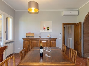 A dining area with a wooden table, chairs, a wine bottle, and glasses. - Rose Adriano Home by Interhome (Cecina)