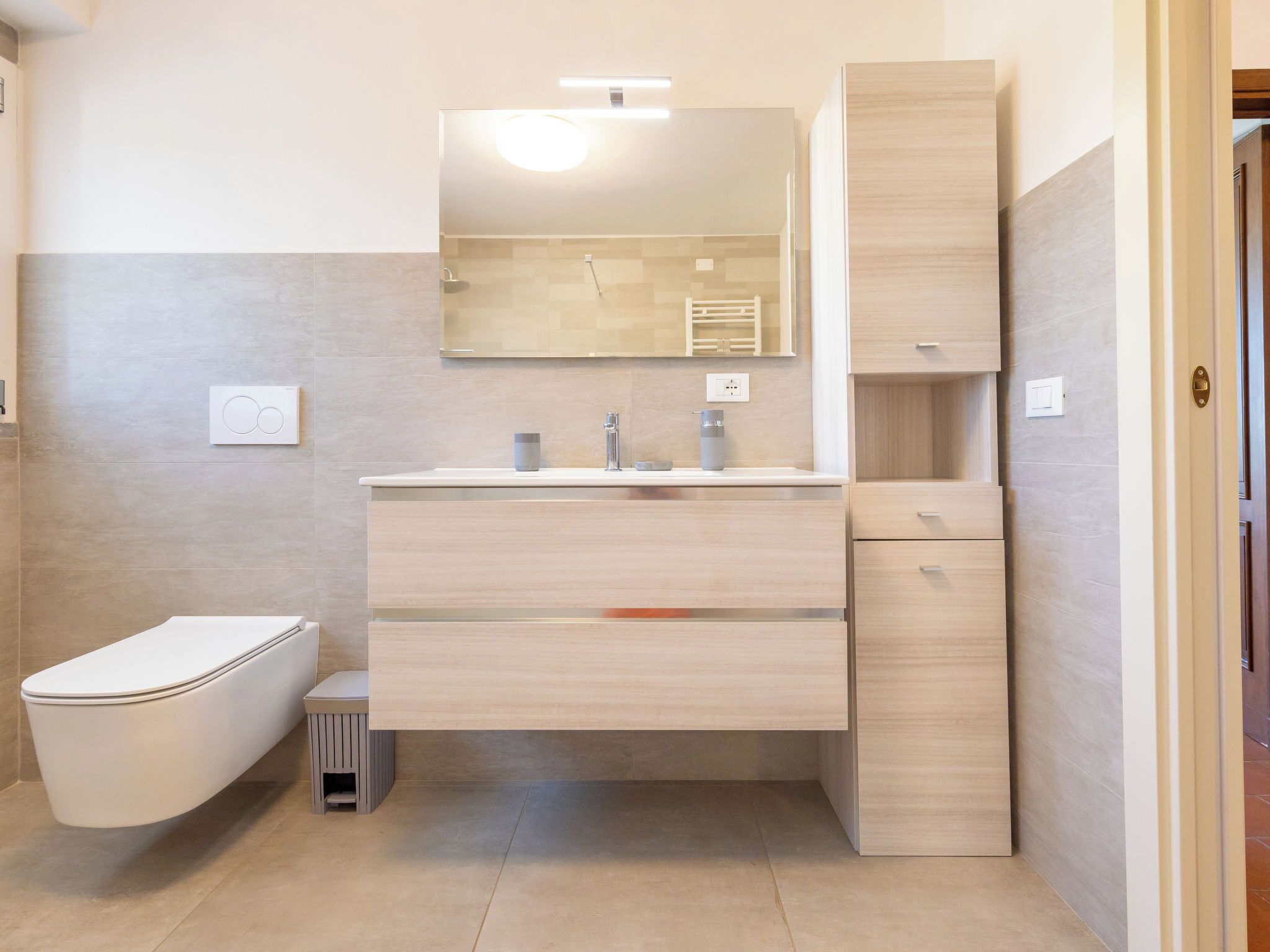 Un baño moderno con inodoro, lavamanos y espejo.