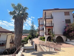A multi-story residential building with balconies, a palm tree, and a clear sky. - Titti e Giba by Interhome (Costarainera)