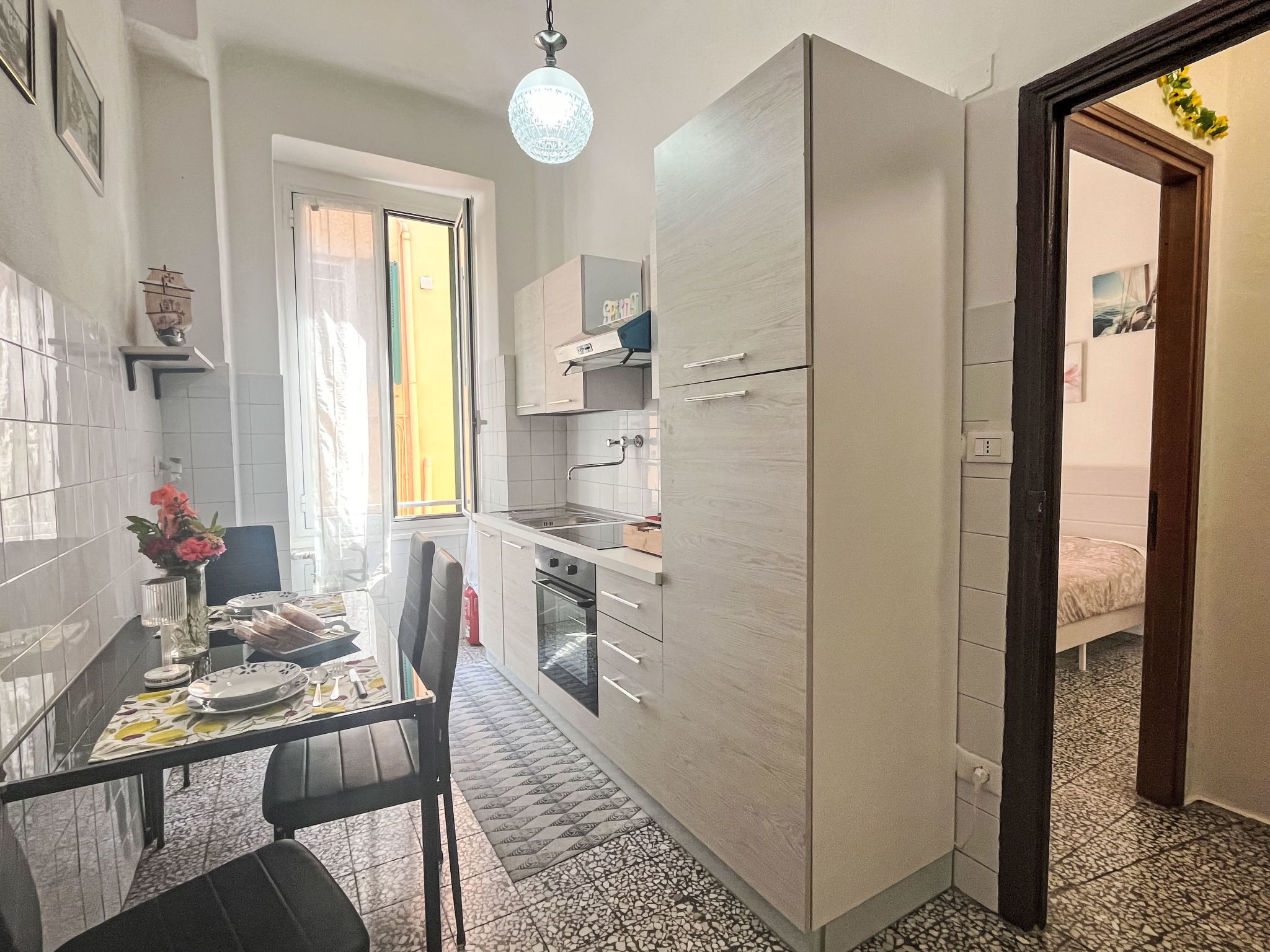 A compact kitchen with a dining table, chairs, a refrigerator, and a small oven.