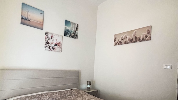 A bedroom with a bed, a nightstand, and wall art. - casa JS by Interhome (Imperia)
