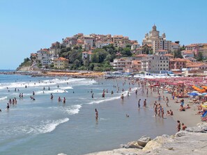 Ein überfüllter Strand mit Menschen, die das Wasser und die Sonne genießen.