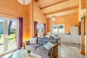 Ein gemütliches Holzhaus mit einer Couch, einem Esstisch und einer Küchenzeile.