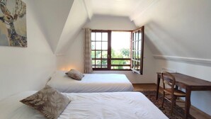 A bedroom with two beds, a desk, and a window with a view of greenery. - Holiday Home 'Gite Les Rosiers' with Private Garden (Eu)