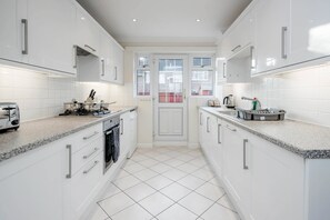 A modern kitchen with white cabinets, granite countertops, and a central island. - Charming 3 Bed Hse Family and Long Stay (Maidenhead)