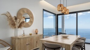 Ein Essbereich mit Holztisch und Stühlen, einem großen Spiegel und Blick auf den Ozean.