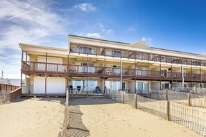 Ein mehrstöckiges Hotel mit Balkonen, einem Sandstrand und einem eingezäunten Pool.