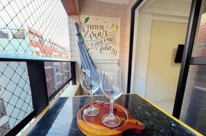 A table with two wine glasses on a wooden tray, a wall with a decorative sign, and a view through a wire mesh. - Pontal Cabo Branco - Miramar (João Pessoa)