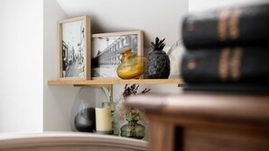 A shelf with framed black and white photographs, a vase, and books. - LE COTTAGE - Charming gîte at the foot of the Château (Combourg)
