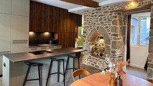 Uma cozinha moderna com lareira de pedra, vigas de madeira e um espaço de bar.