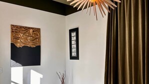 Quarto com cama, luminária pendente, janela e cortina.