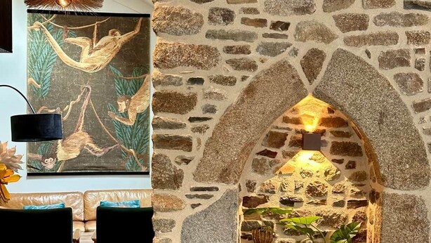 Lareira de pedra com fogão embutido, área de jantar com mesa e cadeiras, e luminária pendente.