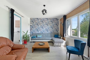 Una sala de estar con un sofá, una silla azul, una mesa de centro y una pared con diseño.