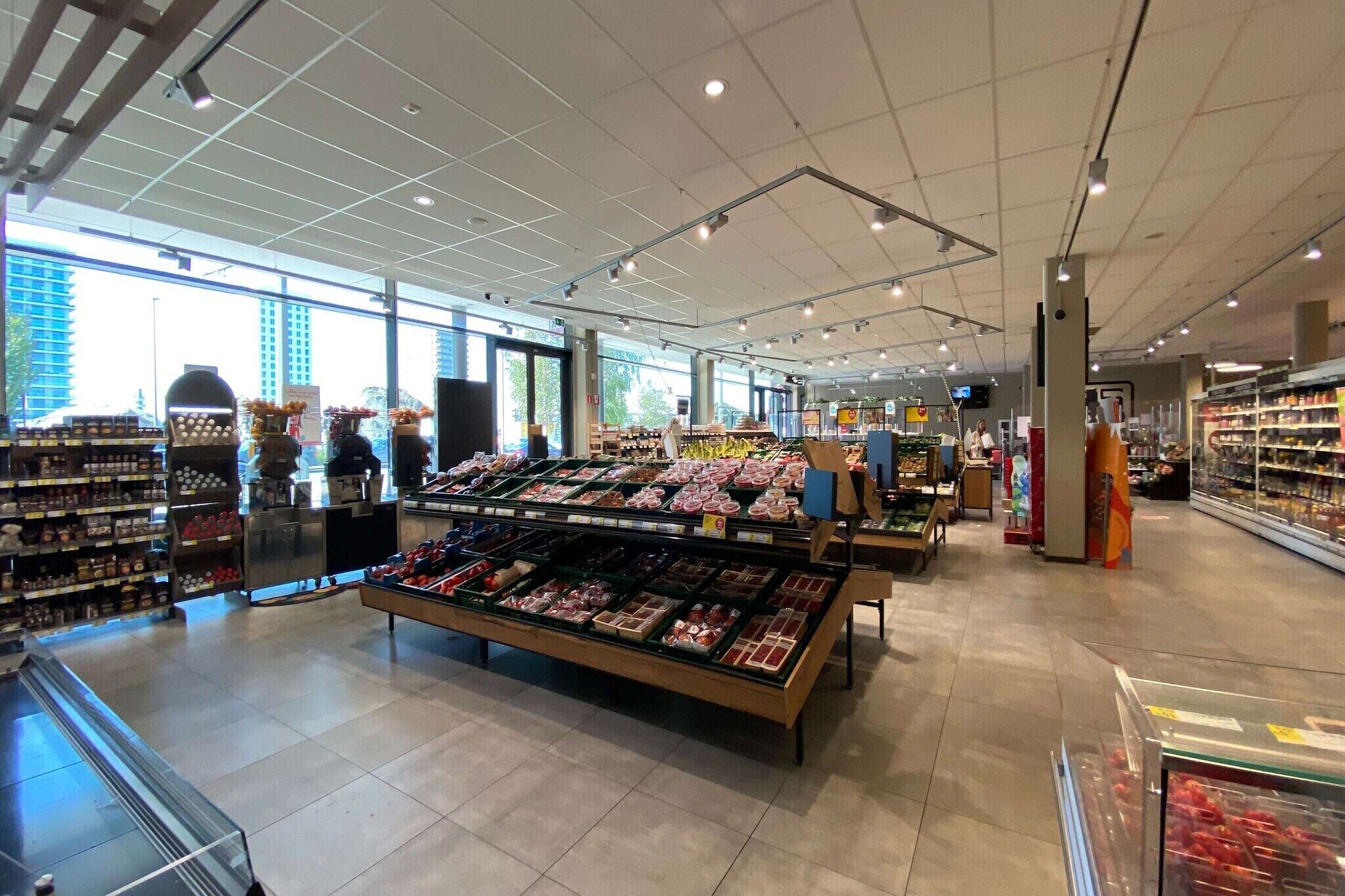 Un grand supermarché avec de larges allées, des rayons réfrigérés et une grande variété de produits exposés.