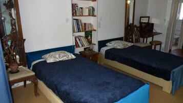 Una habitación con dos camas, una estantería, un espejo y un escritorio.