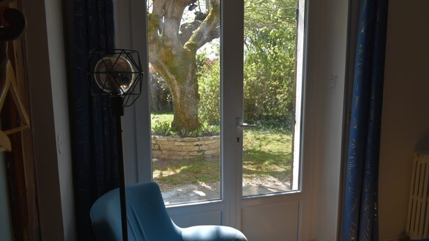 A room with a blue chair, a door leading to an outdoor area, and a radiator on the right.