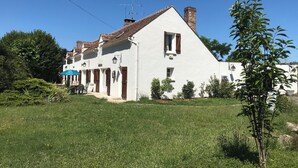 A white building with a sloped roof, multiple windows, and a chimney.