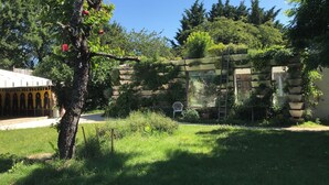 A garden with a tree, a stone wall, and a white chair.
