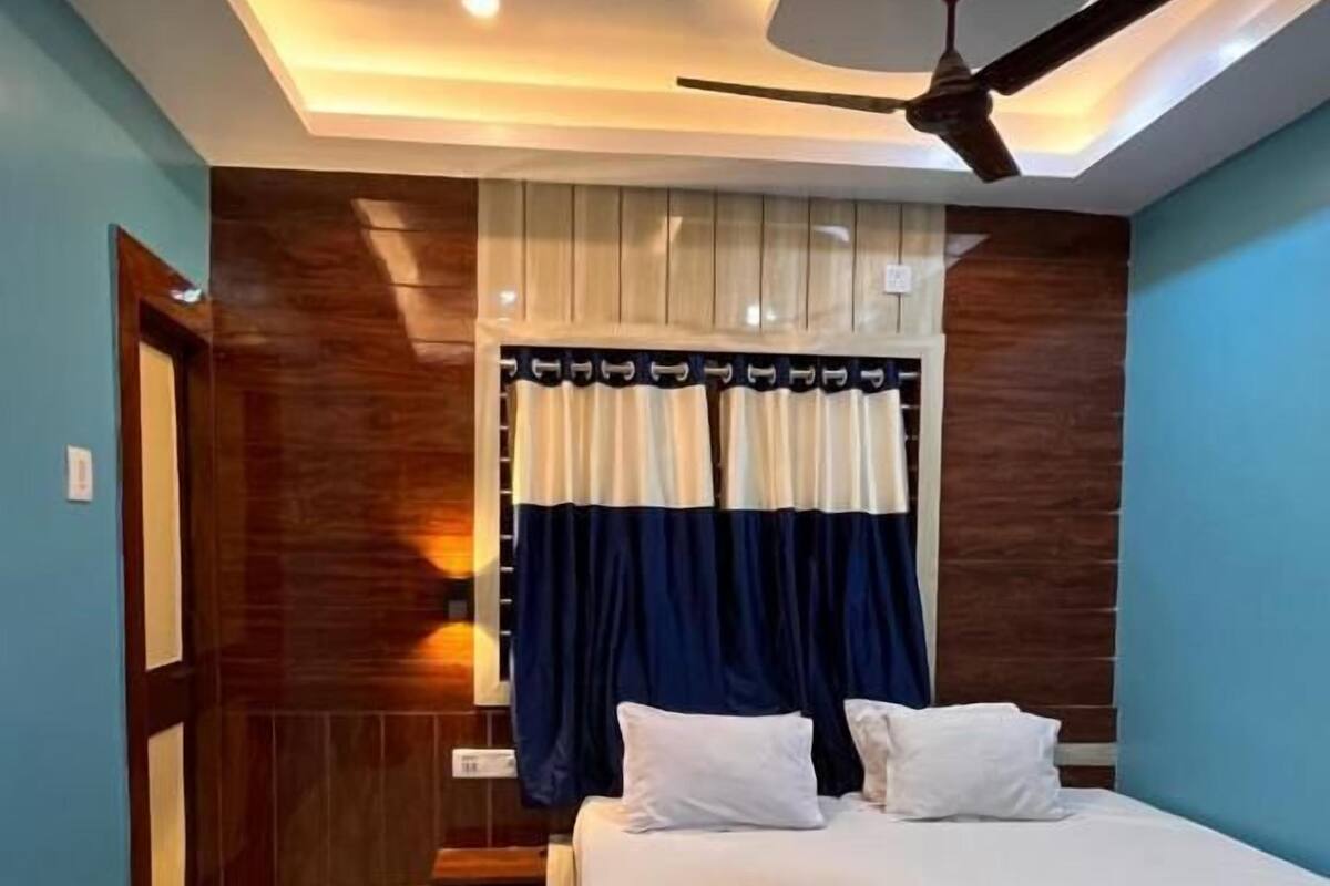 Un dormitorio con una cama, un ventilador de techo y una ventana con cortinas.