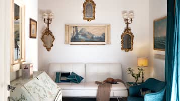 Une pièce avec un canapé blanc, un fauteuil bleu et un tableau accroché au mur.